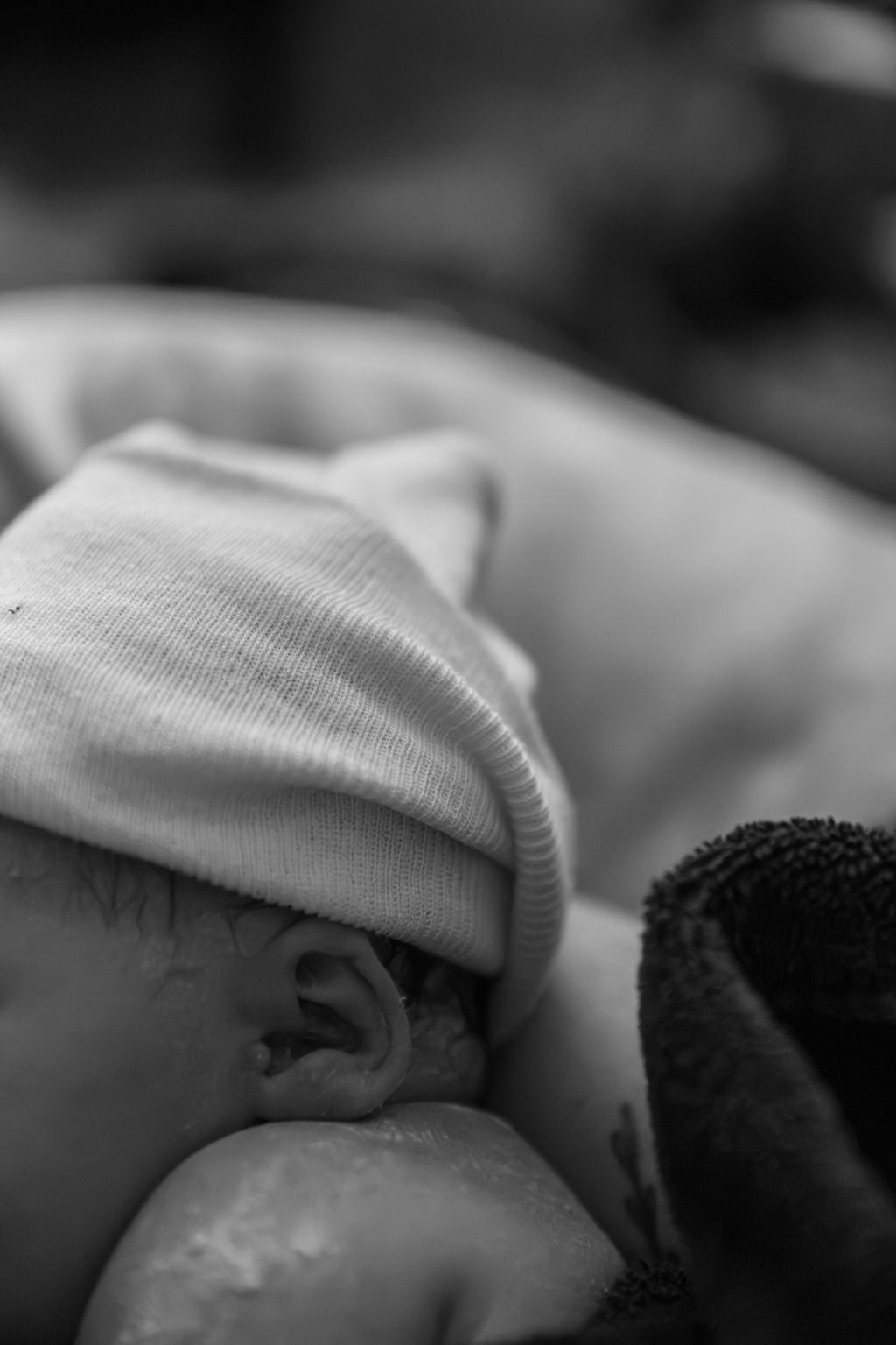 Black and white newborn photography in Las Vegas — baby resting in a knit hat after a home birth