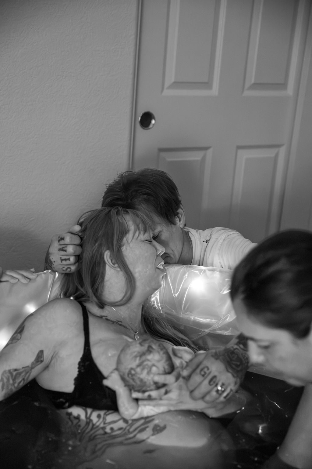 Black and white home birth photography in Las Vegas — partner holding the mother during delivery