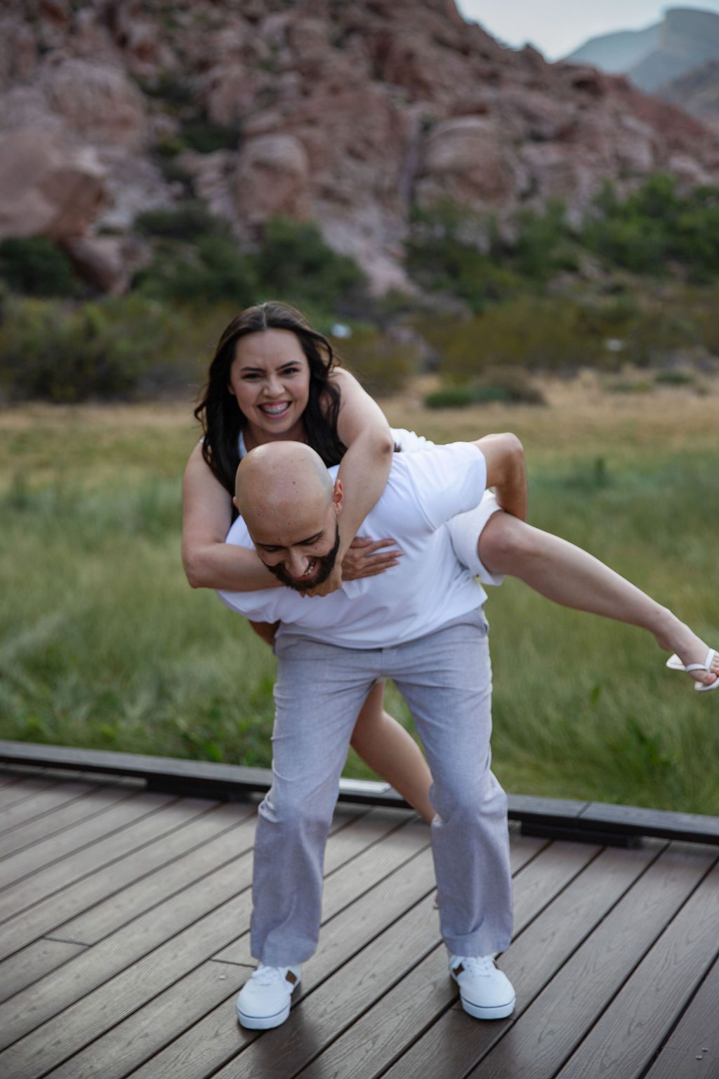 Engagement photography at Red Rock Canyon, Las Vegas — couple laughing mid-piggyback