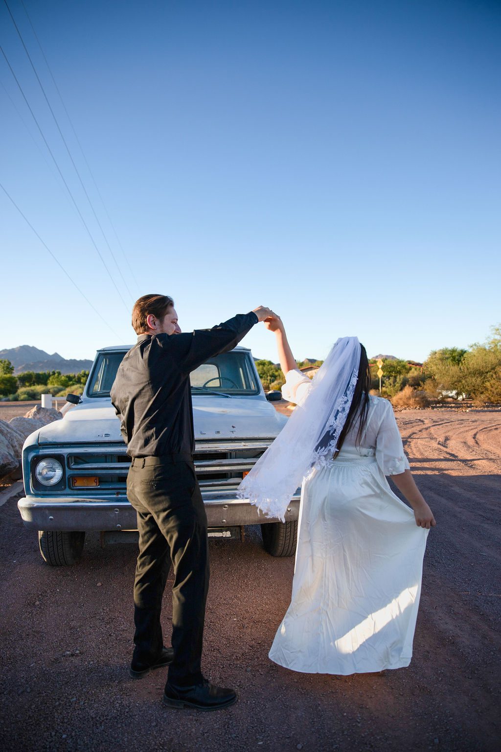 Desert elopement photography near Las Vegas — couple dancing by an old pickup truck