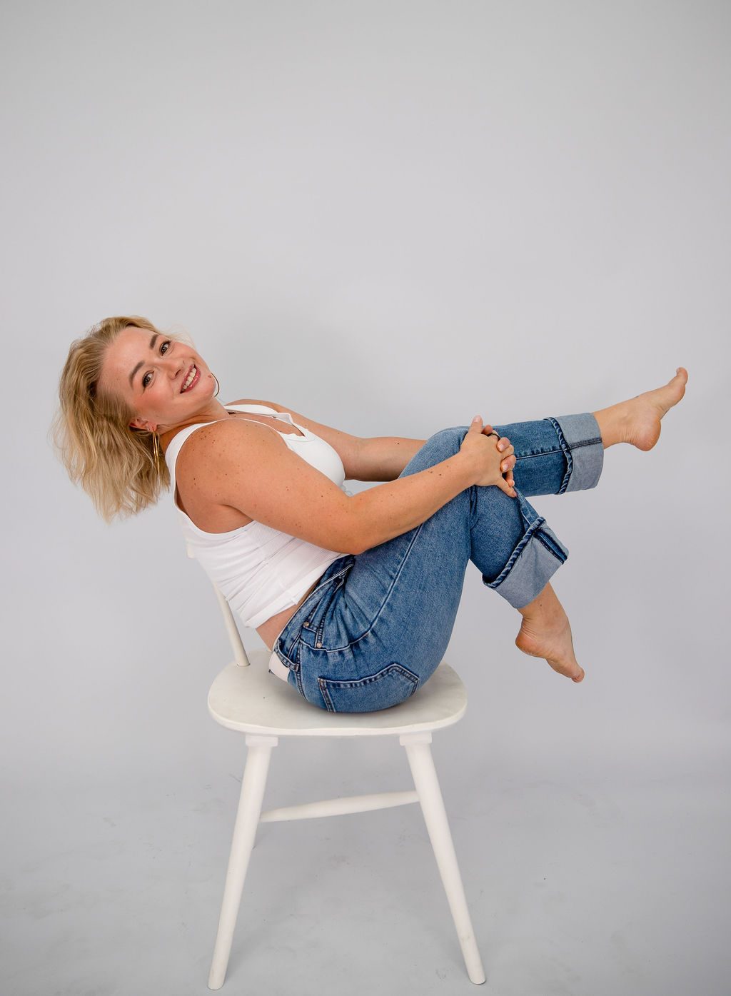 Studio portrait photography in Las Vegas — woman laughing on a white chair