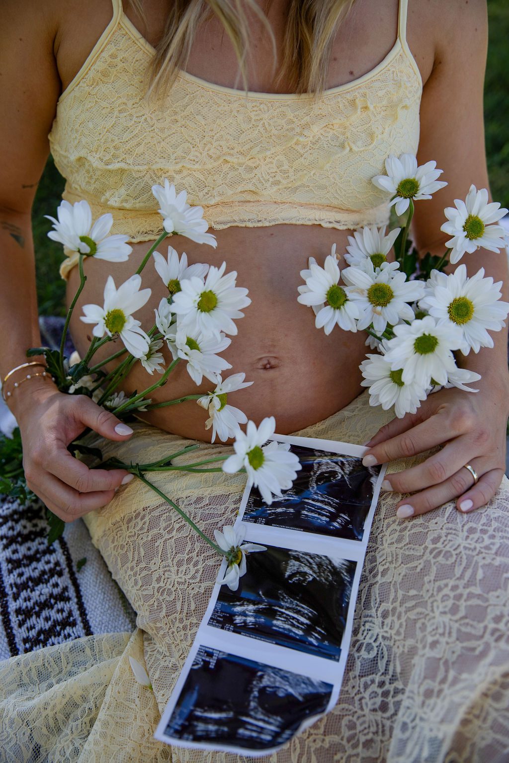 Maternity detail photography in Las Vegas — daisies and ultrasound photos resting on a bump