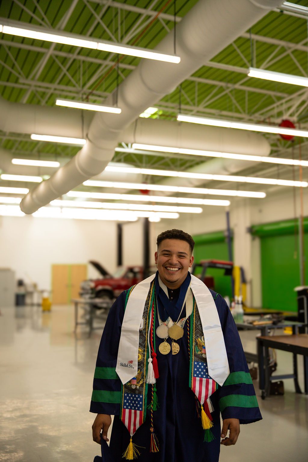Senior photography in Las Vegas — graduate with honour cords in his school auto shop