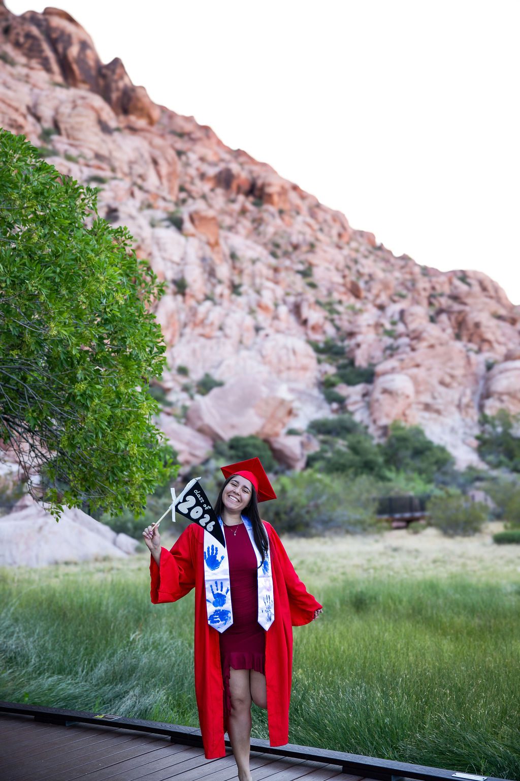 Senior photography at Red Rock Canyon, Las Vegas — graduate in a red gown with a class of 2026 flag