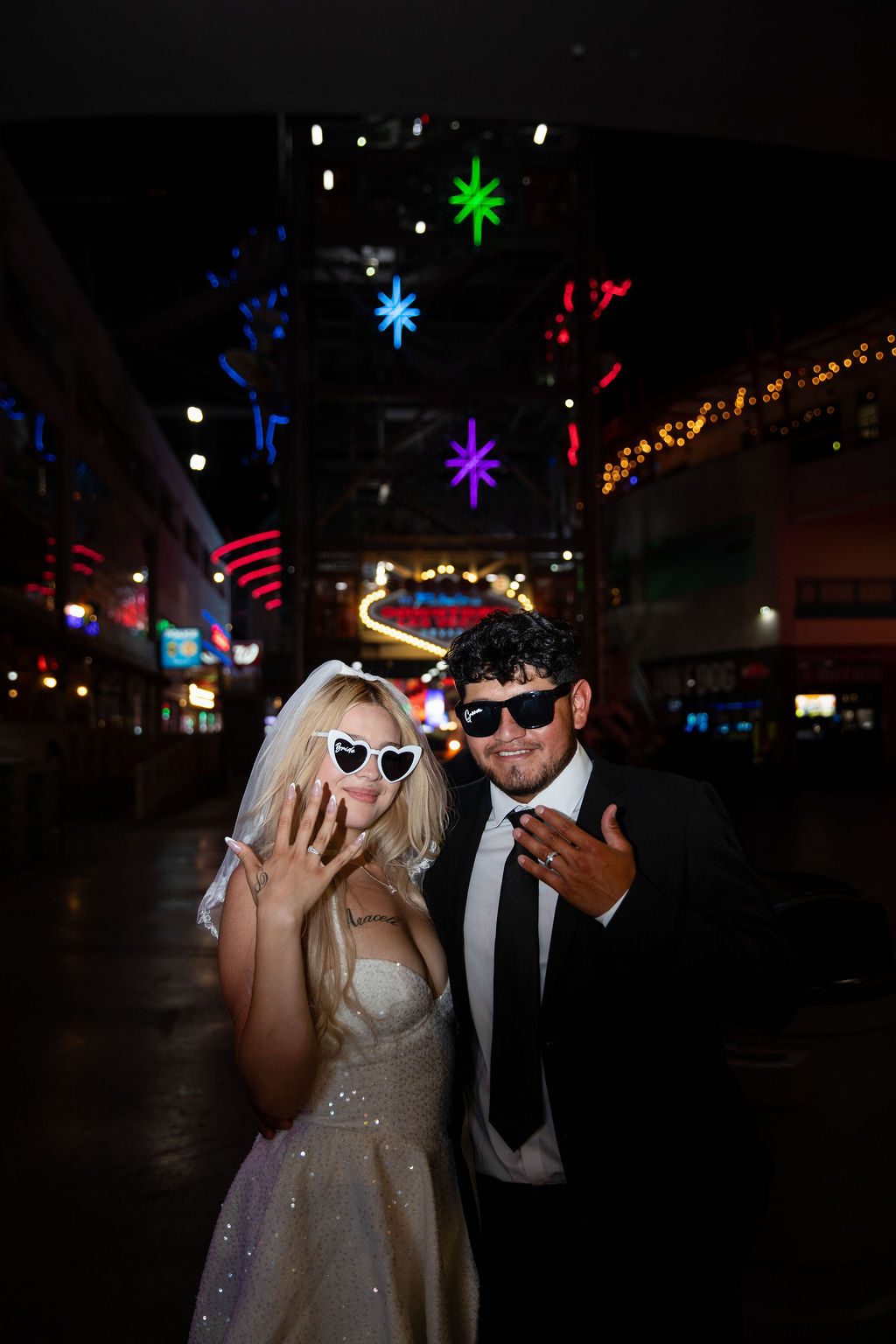 Night wedding photography in downtown Las Vegas — newlyweds showing their rings on Fremont Street